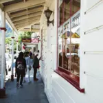 People walking along a covered footpath in the historic main street of Arrowtown.