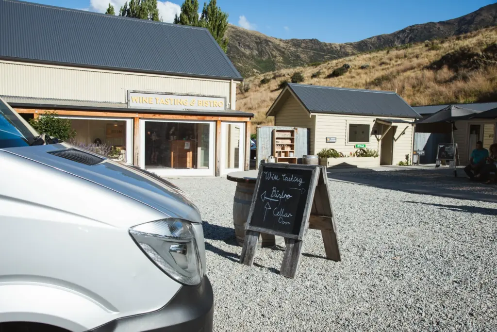 Exterior of a winery and tasting area in Gibbston Valley with a tour van nearby.