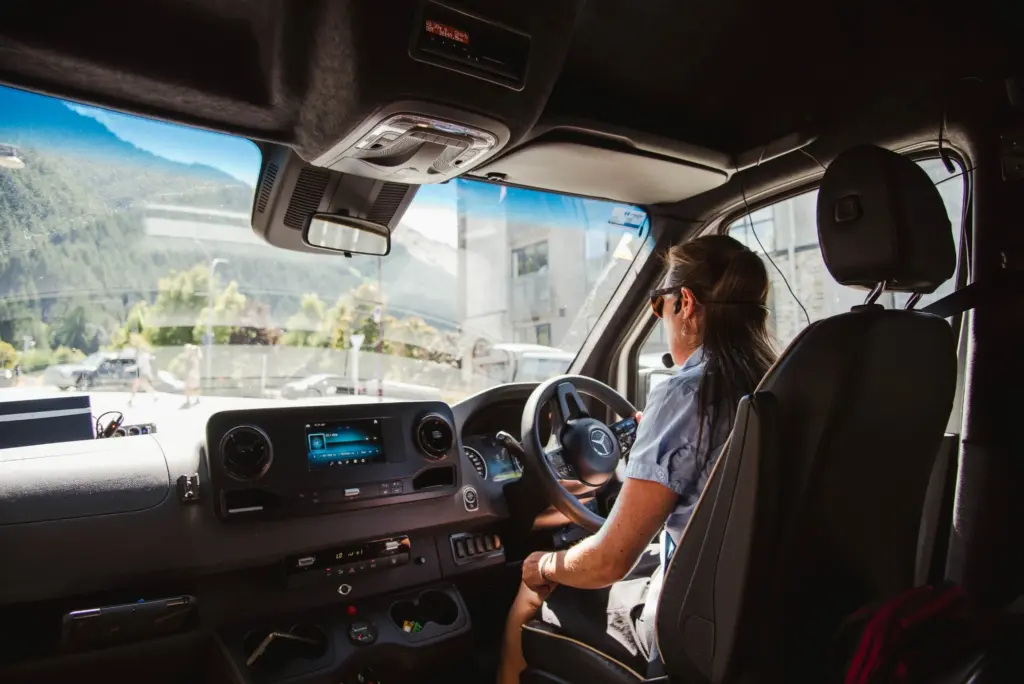 Tour guide driving a Mercedes van through Queenstown during a sightseeing tour.