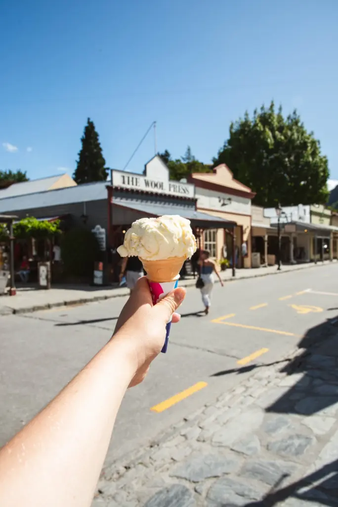Hand holding an ice cream cone on the main street in Arrowtown.