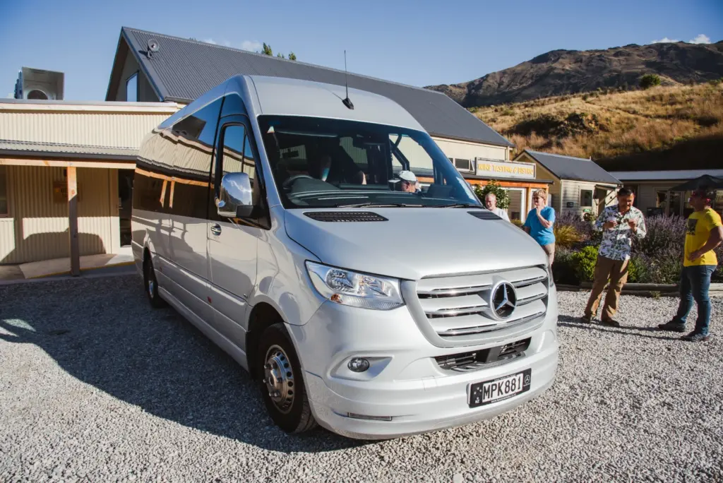 Silver Mercedes tour van parked outside a winery in Gibbston Valley.