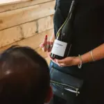 Staff member holding a bottle of Central Otago pinot noir during a wine tasting.