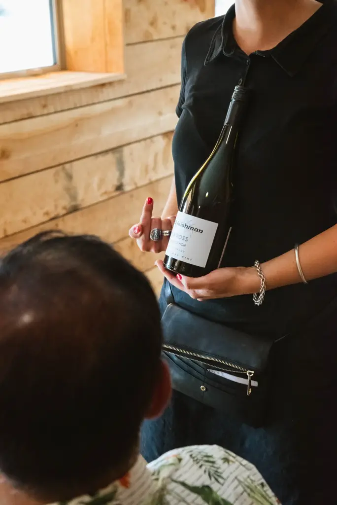 Staff member holding a bottle of Central Otago pinot noir during a wine tasting.