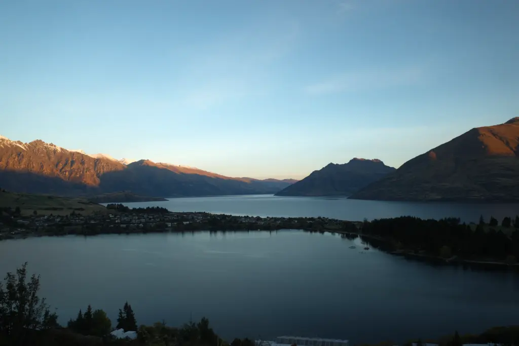 Sunset view over Lake Wakatipu and Queenstown with mountains in the background.
