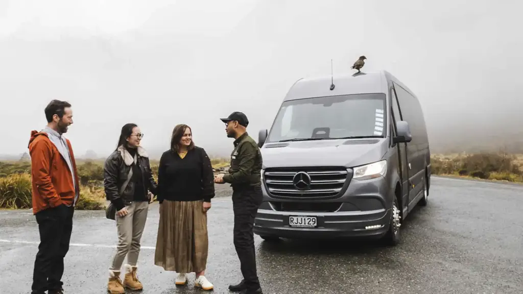 Local guide speaking with guests beside the Milford Sound Business Class tour van