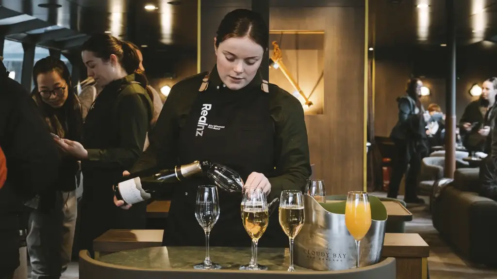 RealNZ crew member pouring sparkling wine on the MV Sinbad Milford Sound cruise