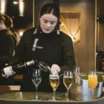 RealNZ crew member pouring sparkling wine on the MV Sinbad Milford Sound cruise