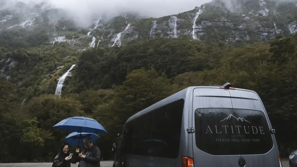 Altitude Tours van parked near waterfalls in Milford Sound after rain