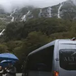 Altitude Tours van parked near waterfalls in Milford Sound after rain